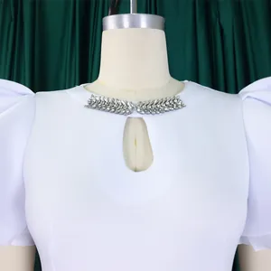 Close-up of elegant white party dress with rhinestone collar and keyhole neckline cutout.
