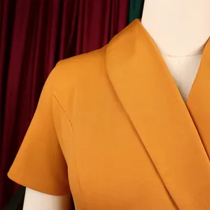 Close-up of elegant shawl collar and shoulder of mustard yellow short-sleeve dress.