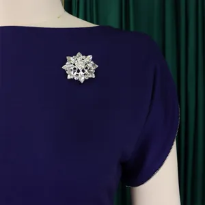 Dettaglio di una scintillante spilla a fiore d'argento su un elegante abito viola a girocollo