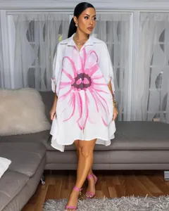 Volledig zicht op een elegante witte oversized overhemdjurk met bloemenprint voor dames