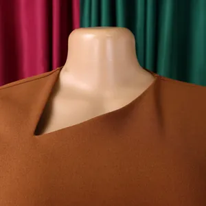 Close-up detail of a professional brown dress with a unique asymmetric neckline design.