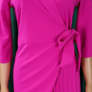 Gros plan d'une robe cache-cœur magenta avec ceinture à nouer et détails plissés