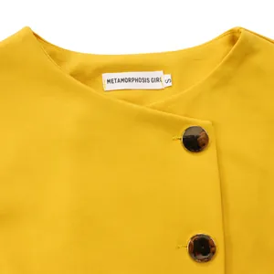 Detail shot of the yellow elegant top neckline with gold buttons and brand label