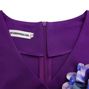 Dettaglio dello scollo a V di un abito viola con etichetta di marca e fiore