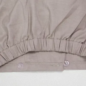Detailansicht des elastischen Saums mit lila Knöpfen an taupefarbenen Pendlerhosen