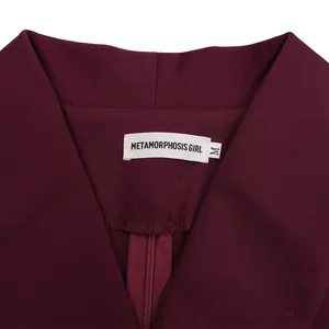 Close-up detail of the refined V-neckline and woven brand label on a burgundy dress