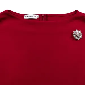 Vista dettagliata dello scollo di un abito rosso vino con spilla a fiore di cristallo