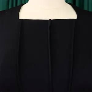 Close-up detail of the elegant square neckline and pleated texture on a black dress.