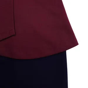 Close-up view of burgundy ruffle hem with stitching detail on a navy color block dress.