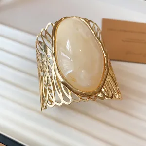 Close-up of vintage hollow-out metal cuff bracelet featuring a large oval cream marble stone.
