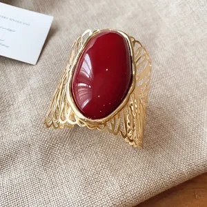 Macro detail of a vintage hollow gold metal arm cuff featuring a large oval red stone