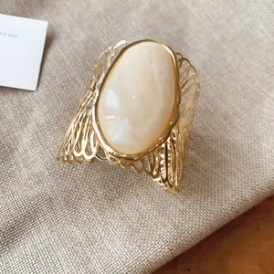 Detailed macro view of retro hollow metal armring featuring a large oval cream stone