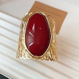 Close-up of vintage gold hollow filigree cuff bracelet with red oval gemstone