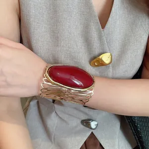 Close-up of vintage hollow gold cuff bracelet featuring a large red oval stone detail