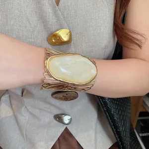 Detailed view of the vintage hollowed-out golden cuff bracelet with a large cream stone.
