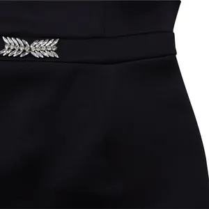 Macro detail of leaf-shaped crystal rhinestone embellishment on black party dress waist