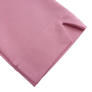 Dettaglio ravvicinato della manica del vestito rosa con cuciture fini e spacco laterale