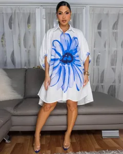 Elegante witte oversized overhemdjurk met grote blauwe bloemenprint en asymmetrische zoom