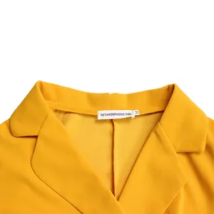 Détail du col blazer classique et de l'étiquette de marque sur une robe plissée jaune chic