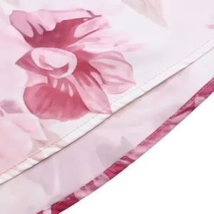 Dettaglio ravvicinato di un vestito floreale rosa con cuciture precise e trama fine