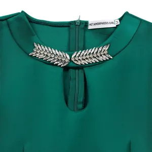 Close-up of green dress neckline with elegant leaf-shaped rhinestone embellishments