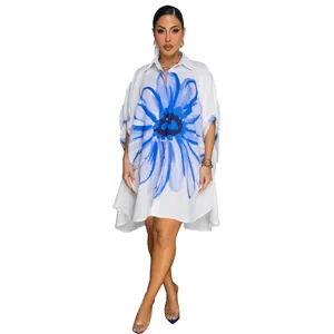 Detail van elegant wit lang shirt met blauwe bloemenprint en asymmetrische zoom