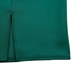 Close-up view of the elegant slit hem and stitching on a dark green bodycon party dress