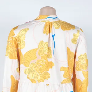 Close-up of elegant yellow floral print dress featuring detailed back pleat design
