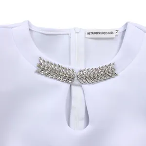 Close-up of white dress neckline with rhinestone leaf details and teardrop cutout