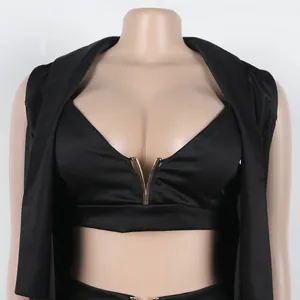 Λεπτομέρεια μαύρου crop top με χρυσό μεταλλικό στοιχείο V από κοστούμι τριών τεμαχίων