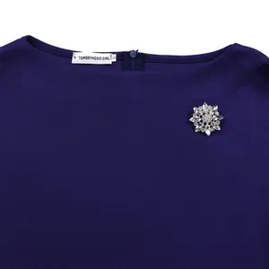 Primo piano dello scollo dell'abito blu navy con elegante spilla a fiore di cristallo