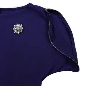 Dettaglio di spilla a fiore in cristallo e cerniera sulla spalla di vestito blu scuro