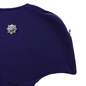 Dettaglio dell'abito viola con spilla a fiocco di neve in strass e cerniera sulla spalla.