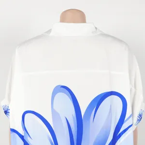 Detailweergave van de grote blauwe bloemenprint op de achterkant van een wit shirt