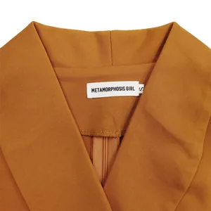 Macro view of the elegant V-neckline on brown dress with Metamorphosis Girl brand tag