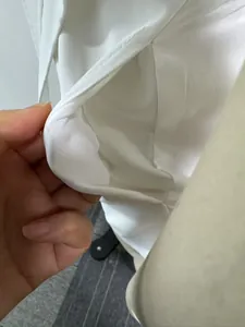 Detailansicht der hochwertigen Stoff- und Taschendetails des weißen Jumpsuits mit V-Ausschnitt