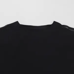 Primer plano del elegante cuello redondo y la textura de gasa de un vestido poncho negro