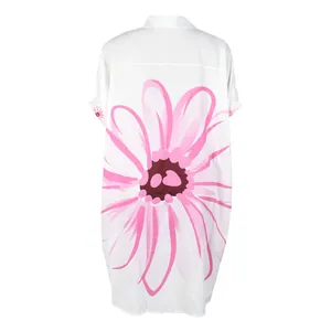 Detail van de grote roze bloemenprint op de achterkant van de witte lange hemdjurk