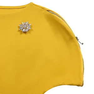 Dettaglio ravvicinato di vestito giallo con spilla a fiocco di neve in cristallo