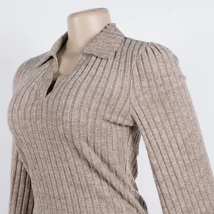 Macro detail of beige ribbed polo collar knit top featuring elegant lantern sleeves.