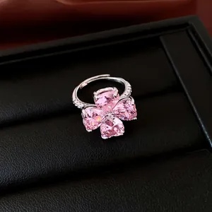 Gedetailleerd zicht van een klaverring met roze hartvormige zirkonia's op zwarte doos.