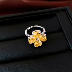 Detailweergave van een elegante klaverring met gele zirkoonhartjes op een sieradendoosje