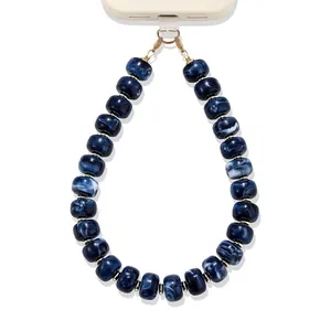 Detailweergave van de blauwe marmeren hars kralen telefoonriem met gouden sluiting.