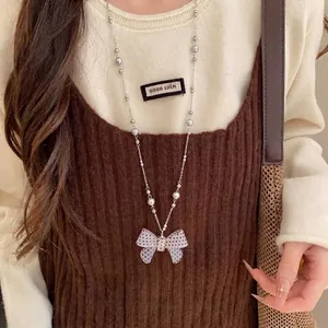 Collana delicata con fiocco a pois e perle indossata da una modella in un set di lifestyle