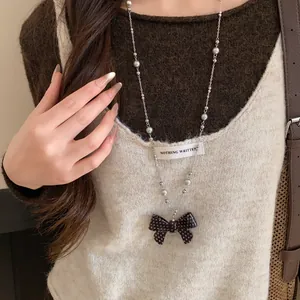 Dettaglio di una collana in argento con pendente a fiocco a pois bianchi e neri.