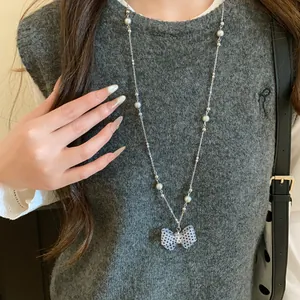 Primo piano di una dolce collana a fiocco a pois bianchi e neri con finte perle bianche