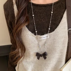 Dettaglio di una collana con ciondolo a fiocco a pois bianchi e neri e perline argento
