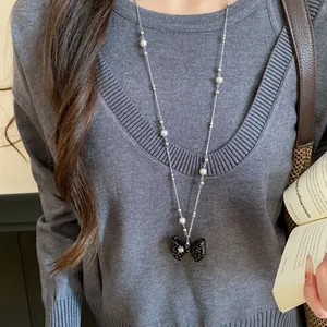 Dettaglio ravvicinato di un'elegante collana di perle con ciondolo a fiocco a pois neri.