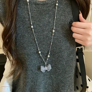 Primo piano di una collana d'argento con ciondolo a fiocco a pois bianchi e neri