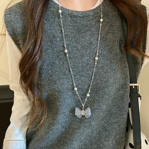 Dettaglio di una collana con fiocco a pois bianco e nero e perle bianche su gilet.